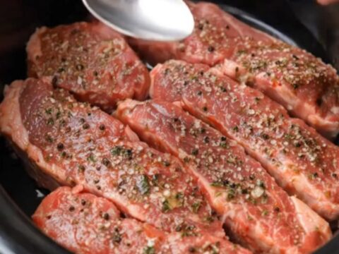 Tender, glistening slow-cooked steak strips served on a white plate with garlic butter sauce.