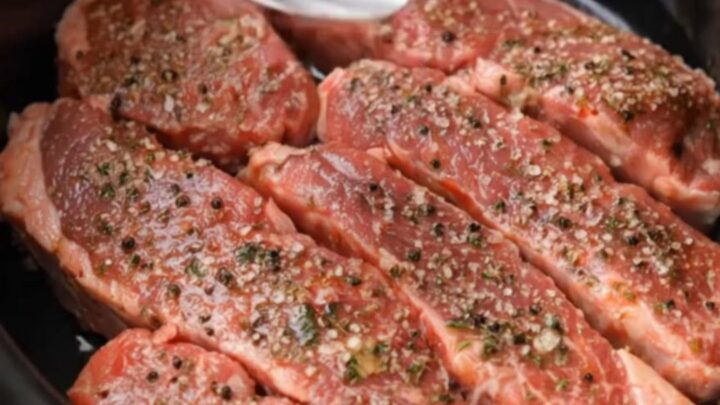 Tender, glistening slow-cooked steak strips served on a white plate with garlic butter sauce.