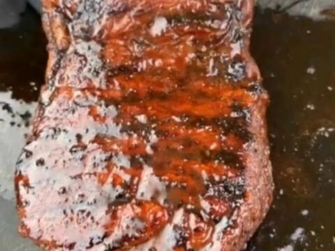 A perfectly grilled steak with visible char marks and a glossy glaze on a wooden cutting board.
