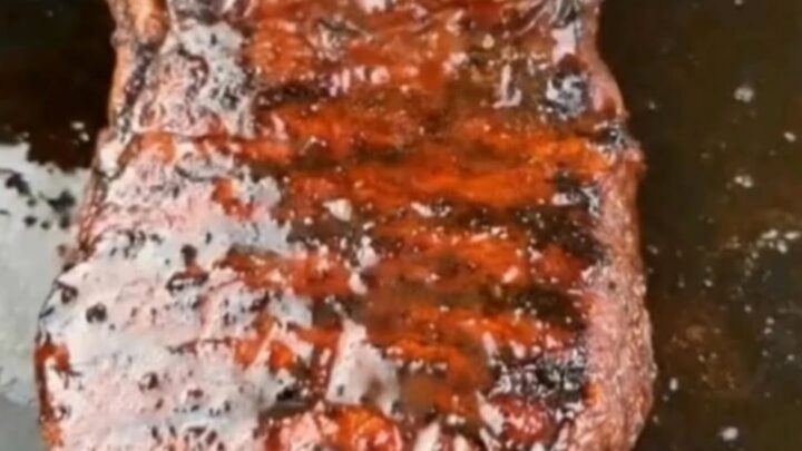 A perfectly grilled steak with visible char marks and a glossy glaze on a wooden cutting board.