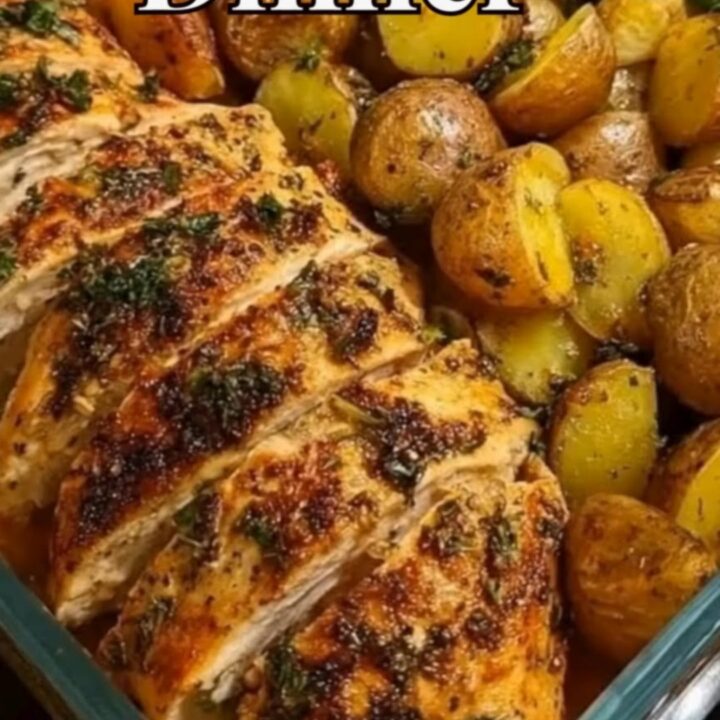 A glass baking dish containing golden roasted chicken breasts, baby potatoes, and green beans.