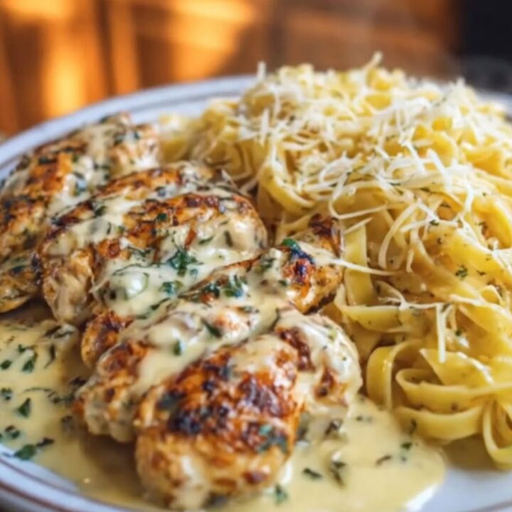 A close-up of creamy garlic chicken and fettuccine alfredo on a white plate.