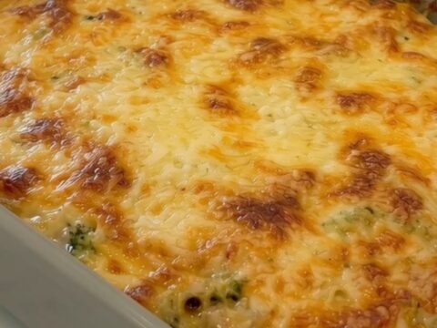 A golden, bubbly potato and broccoli casserole in a grey ceramic dish.
