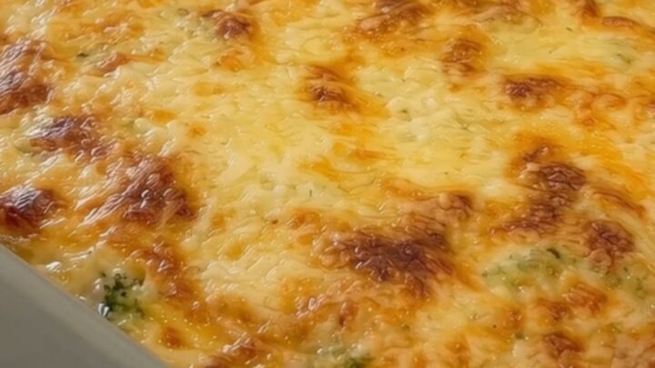 A golden, bubbly potato and broccoli casserole in a grey ceramic dish.