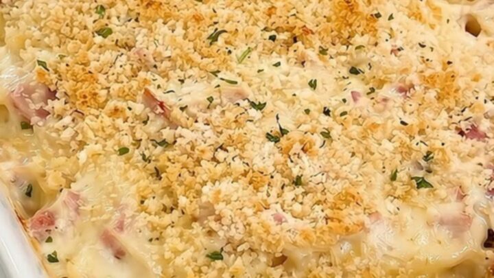 A steaming scoop of creamy chicken cordon bleu pasta casserole in a white ceramic dish.