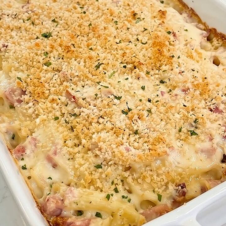A steaming scoop of creamy chicken cordon bleu pasta casserole in a white ceramic dish.