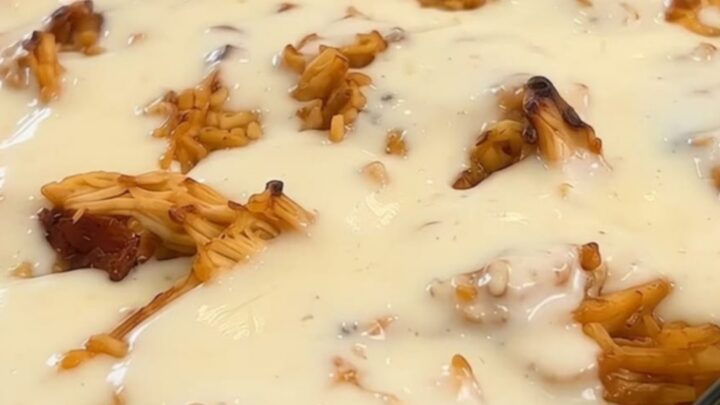 A steaming, creamy chicken and rice casserole in a glass baking dish with melted white queso on top.