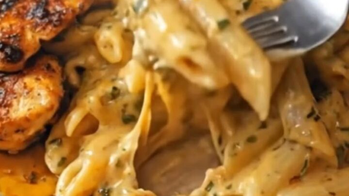 A close-up of creamy Cajun chicken Alfredo with golden-brown chicken slices and fresh herbs.