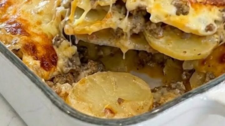 A golden, cheesy potato and ground beef casserole in a white ceramic dish.
