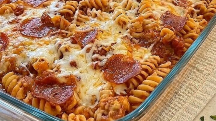 A bubbly and cheesy pizza pasta bake in a glass dish with long strands of melted mozzarella.