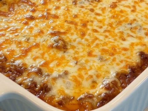 A bubbly, golden-brown mozzarella topped cowboy casserole in a light-blue baking dish.