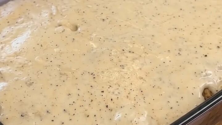 A golden, baked breakfast casserole in a glass dish, featuring layers of tater tots, sausage
