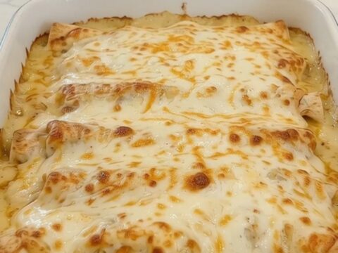 A hot, cheesy chicken bake in a white ceramic casserole dish with steam rising.