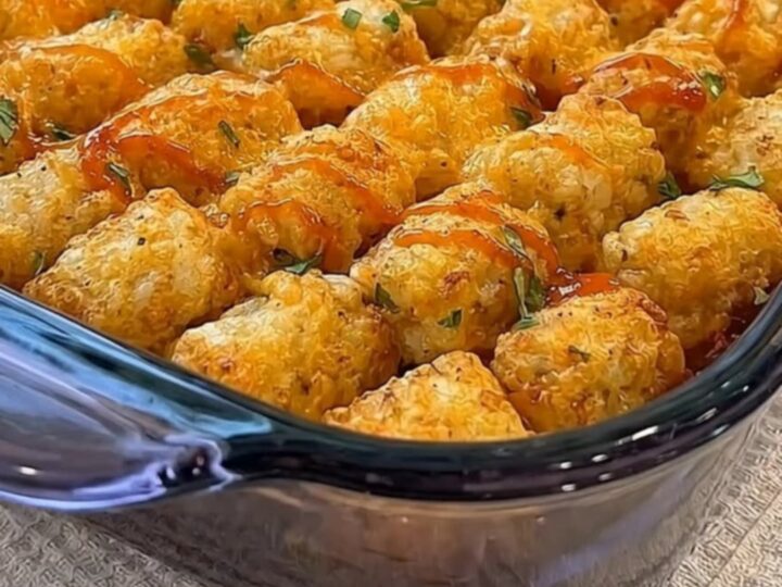 A golden, crispy tater tot casserole in a glass dish with a melted cheese pull.