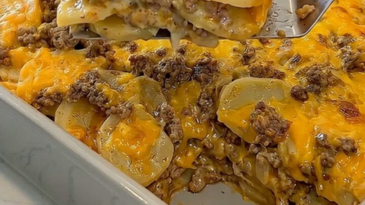 A golden, bubbling cheesy hamburger potato casserole in a grey ceramic dish.