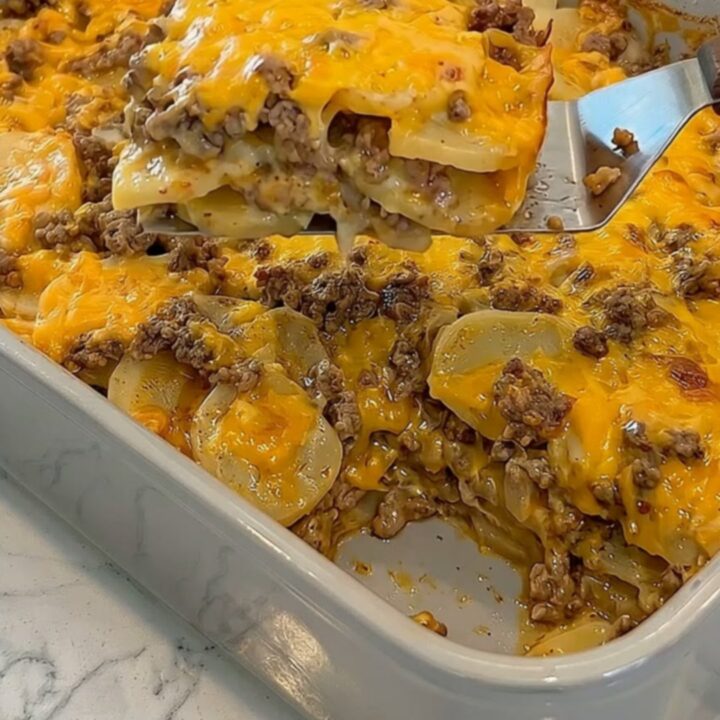 A golden, bubbling cheesy hamburger potato casserole in a grey ceramic dish.