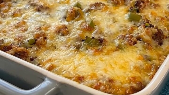 A golden-brown cheesy Philly cheesesteak casserole in a grey baking dish.