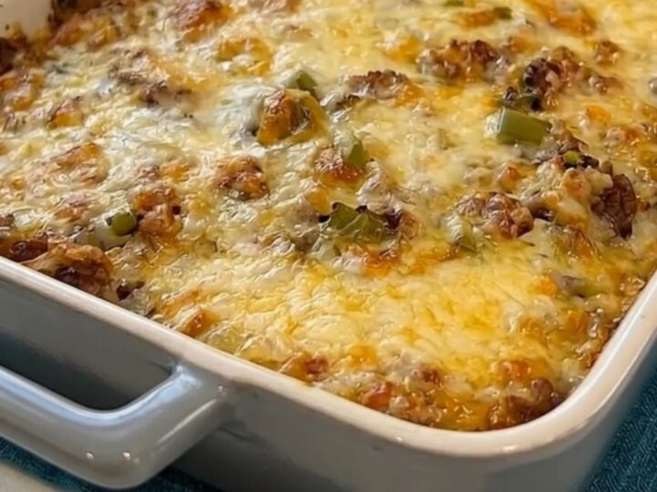A golden-brown cheesy Philly cheesesteak casserole in a grey baking dish.
