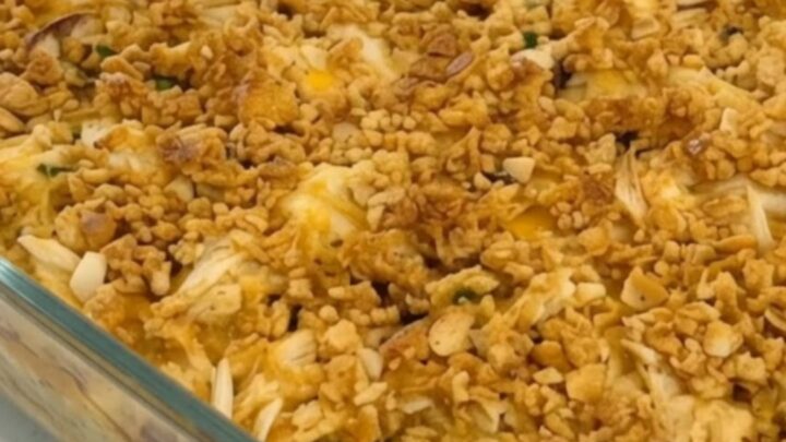 A golden-brown chicken casserole in a glass dish with a crispy Ritz cracker topping.