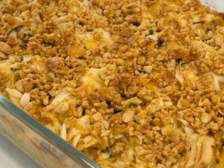 A golden-brown chicken casserole in a glass dish with a crispy Ritz cracker topping.