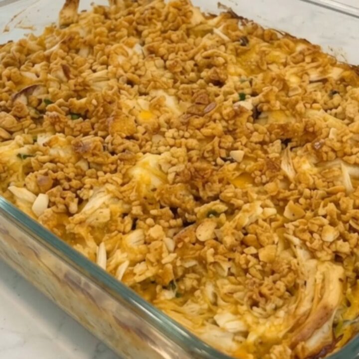 A golden-brown chicken casserole in a glass dish with a crispy Ritz cracker topping.