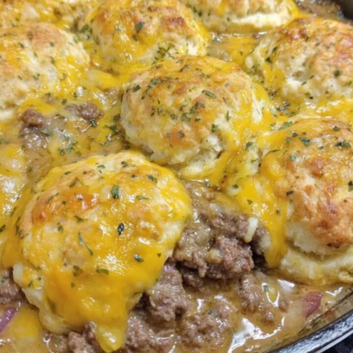 A golden-brown Cheddar Bay Hamburger Casserole in a sizzling cast-iron skillet garnished with parsley.