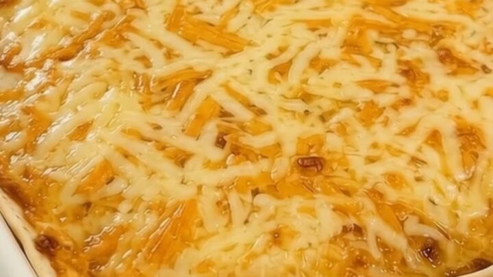 A steaming, golden-brown cheesy taco lasagna served in a white baking dish with a spatula ready to lift a portion.