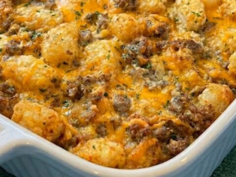 A golden-brown breakfast casserole with melted cheese and crispy tater tots in a white ceramic dish.