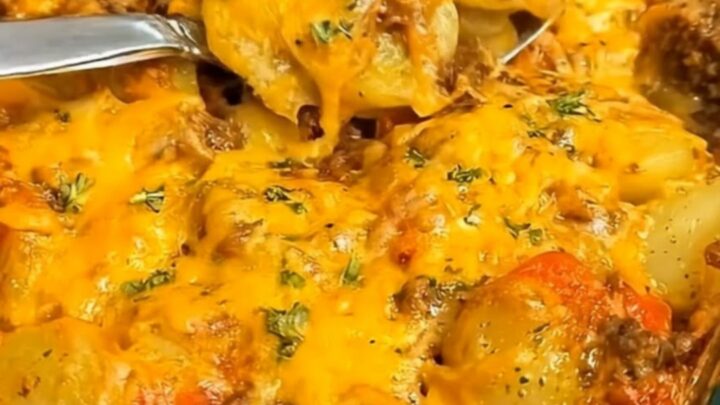 A glass baking dish filled with a cheesy hobo ground beef and potato casserole.