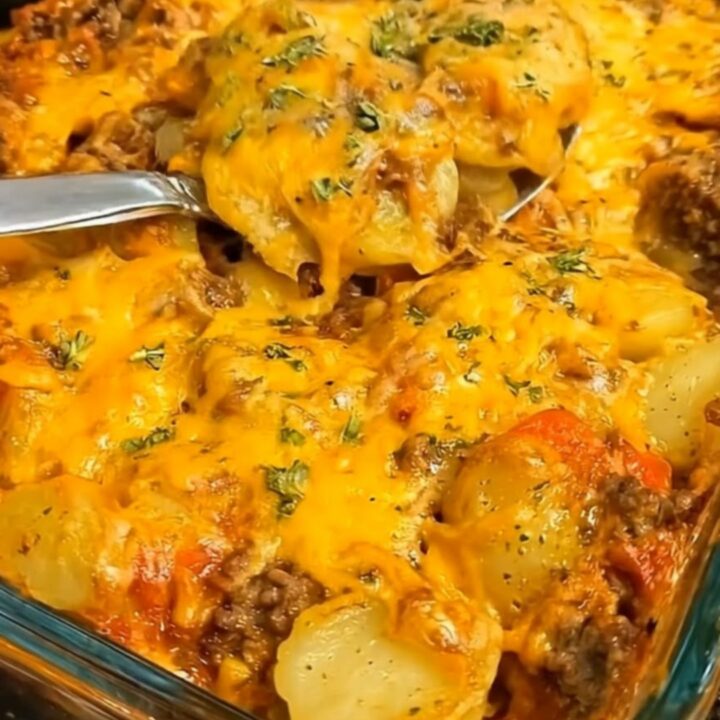 A glass baking dish filled with a cheesy hobo ground beef and potato casserole.