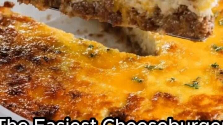 A golden-baked cheeseburger pie in a white ceramic dish with a slice being lifted by a metal server.