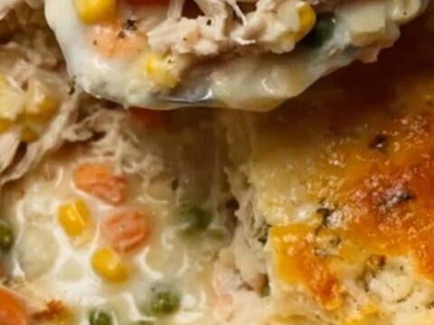 A golden, fluffy cheddar biscuit topping over a bubbling, creamy chicken and vegetable cobbler in a casserole dish.
