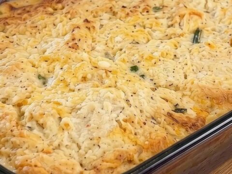 A golden, bubbling cheddar biscuit chicken pot pie in a glass baking dish.