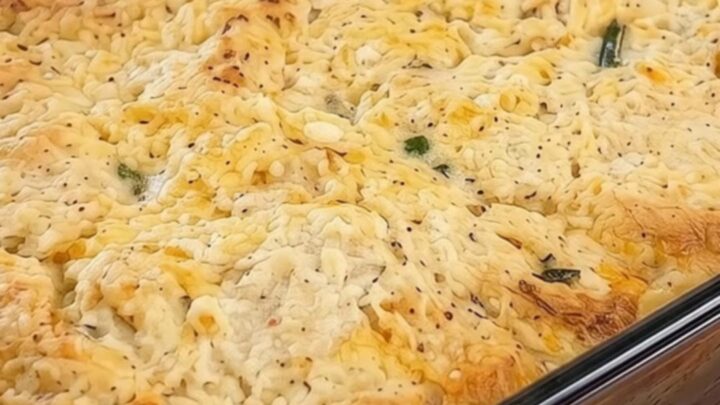 A golden, bubbling cheddar biscuit chicken pot pie in a glass baking dish.