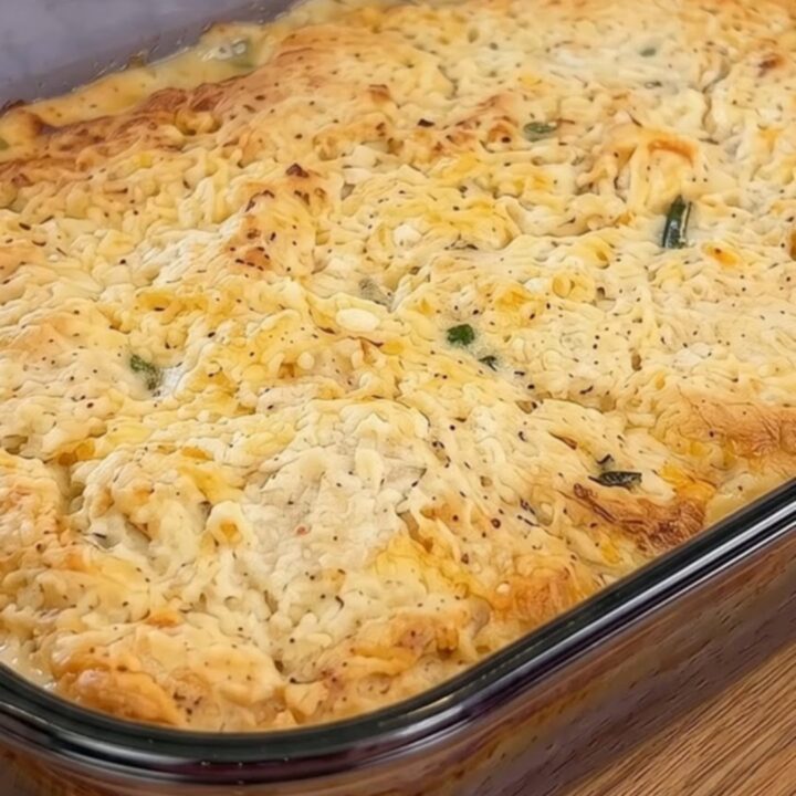A golden, bubbling cheddar biscuit chicken pot pie in a glass baking dish.
