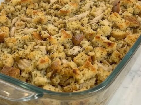 A golden brown creamy chicken and herb stuffing bake in a glass dish.
