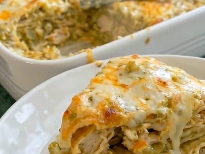 A warm, cheesy green chili chicken enchilada casserole in a white ceramic baking dish.