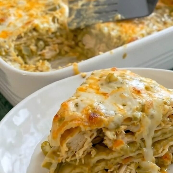A warm, cheesy green chili chicken enchilada casserole in a white ceramic baking dish.