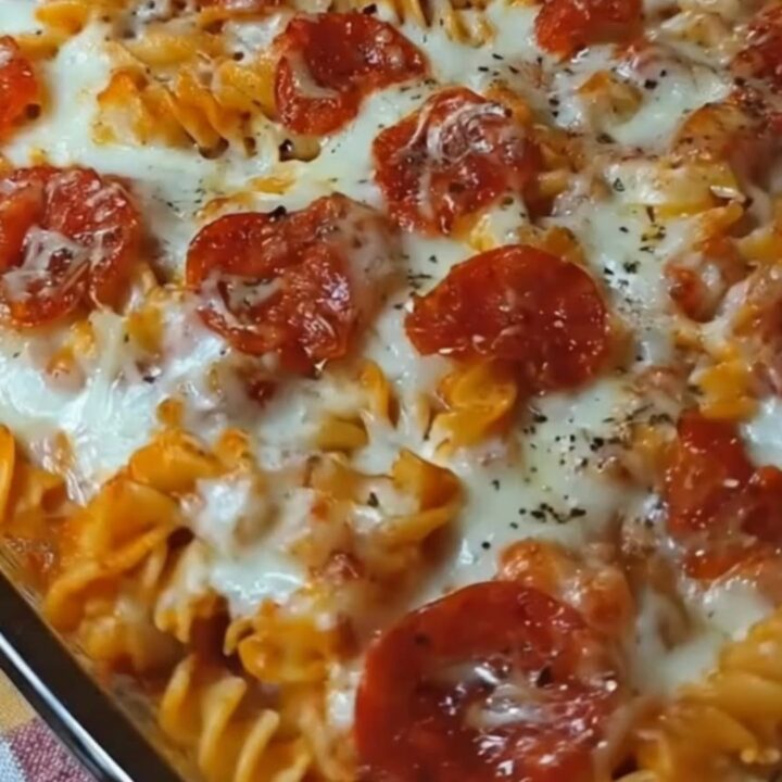 A steaming hot pizza pasta casserole in a glass baking dish with melted mozzarella and pepperoni.