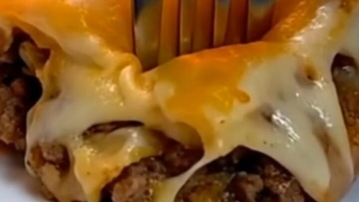 A slice of cheesy Mexican lasagna being lifted from a glass baking dish with a metal spatula.