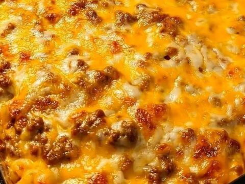 A golden, bubbling cheeseburger casserole in a glass baking dish sitting on a granite countertop.