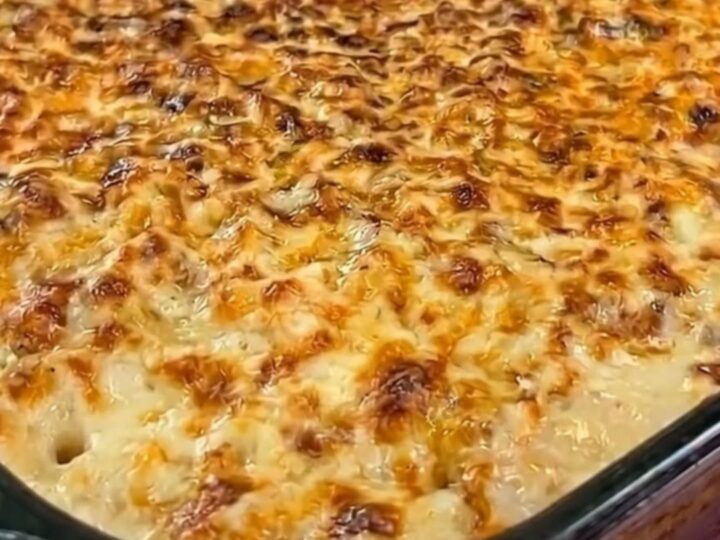 A golden, bubbling creamy mashed potato and chicken casserole in a glass dish.