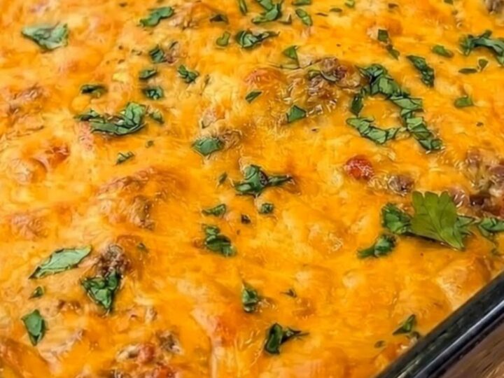 A cheesy taco beef and chip casserole in a 9x13 glass dish with a golden, bubbly cheese top.