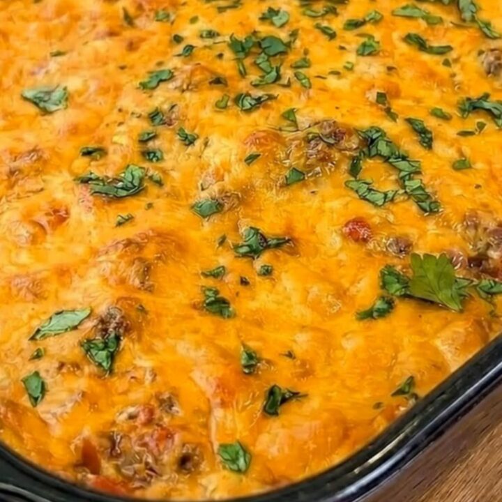 A cheesy taco beef and chip casserole in a 9x13 glass dish with a golden, bubbly cheese top.