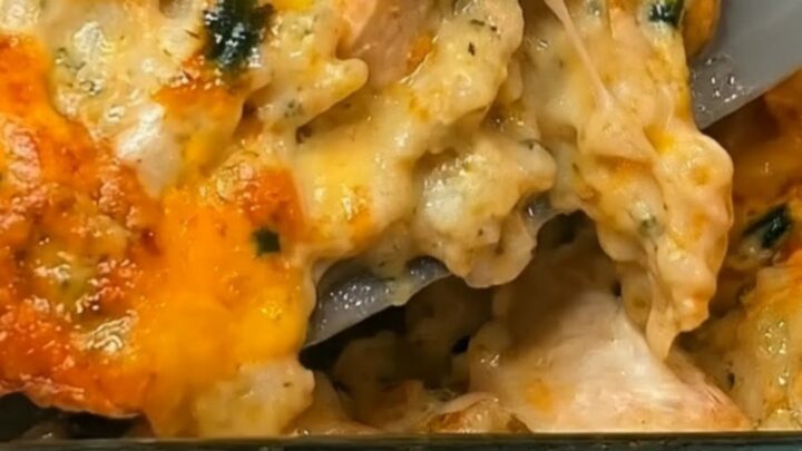 A golden-brown, cheesy chicken and broccoli rice casserole in a glass baking dish, steaming hot and ready to serve.