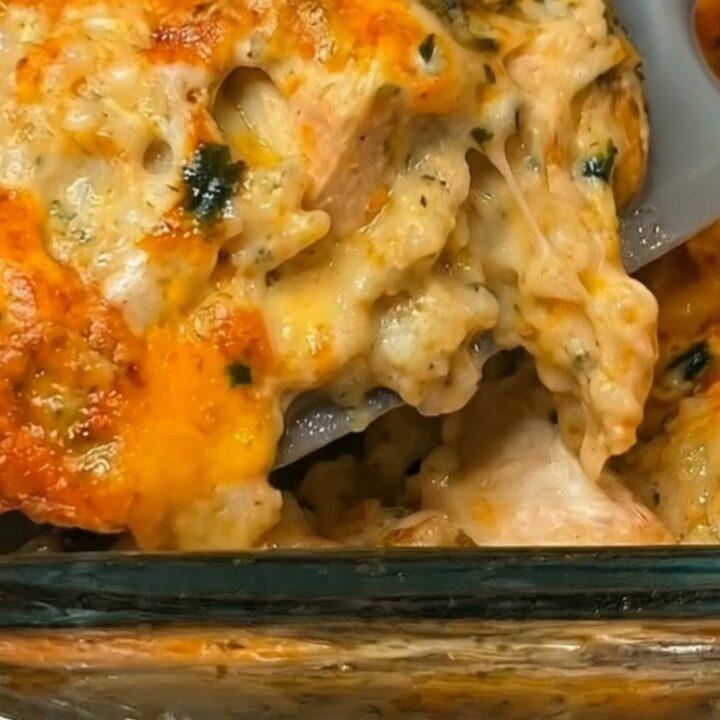 A golden-brown, cheesy chicken and broccoli rice casserole in a glass baking dish, steaming hot and ready to serve.