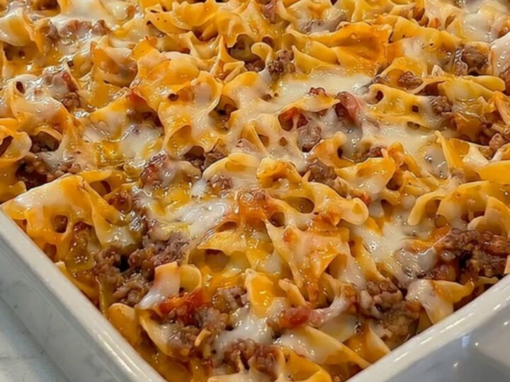 A steaming cheesy ground beef noodle casserole in a grey ceramic dish.