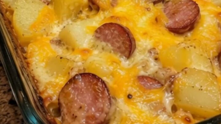 A steaming portion of creamy loaded sausage and potato bake with melted cheddar cheese in a baking dish.