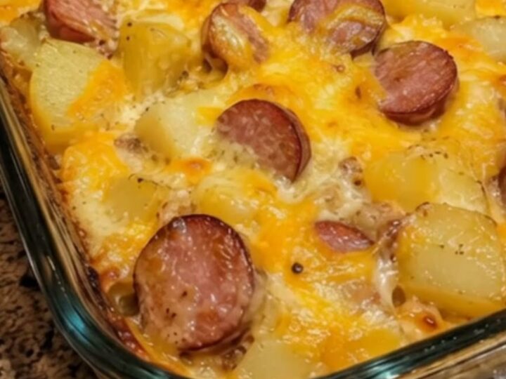 A steaming portion of creamy loaded sausage and potato bake with melted cheddar cheese in a baking dish.