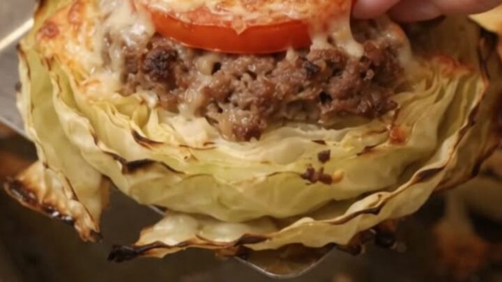 A roasted cheesy cabbage and beef round being lifted with a spatula, showing melting golden cheese.